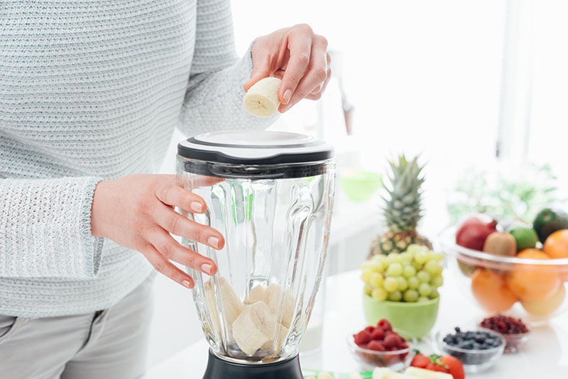 Woman putting a banana in a blender