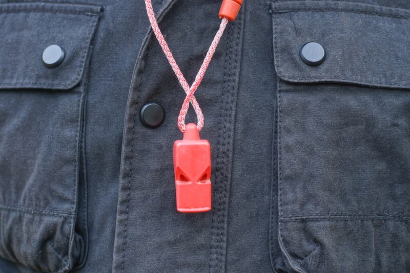 red plastic whistle hanging on a man's chest