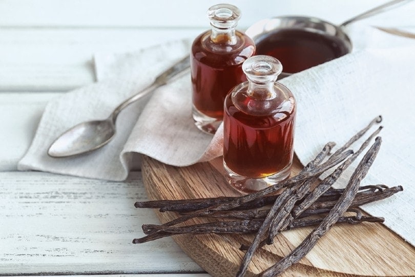 bottles with aromatic extract and dry vanilla beans on board