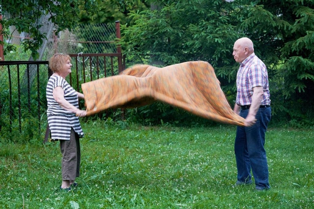 elderly couple cleaning blanket outside