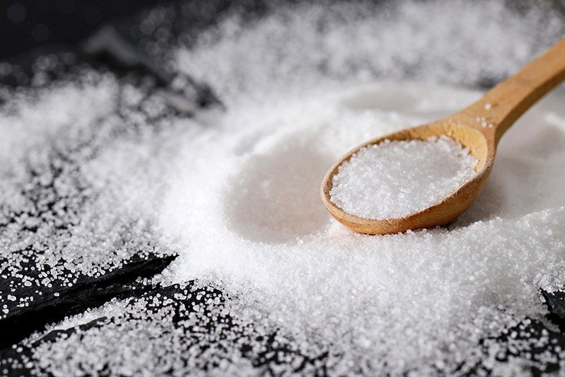 salt on a wooden spoon and all over the black clothe