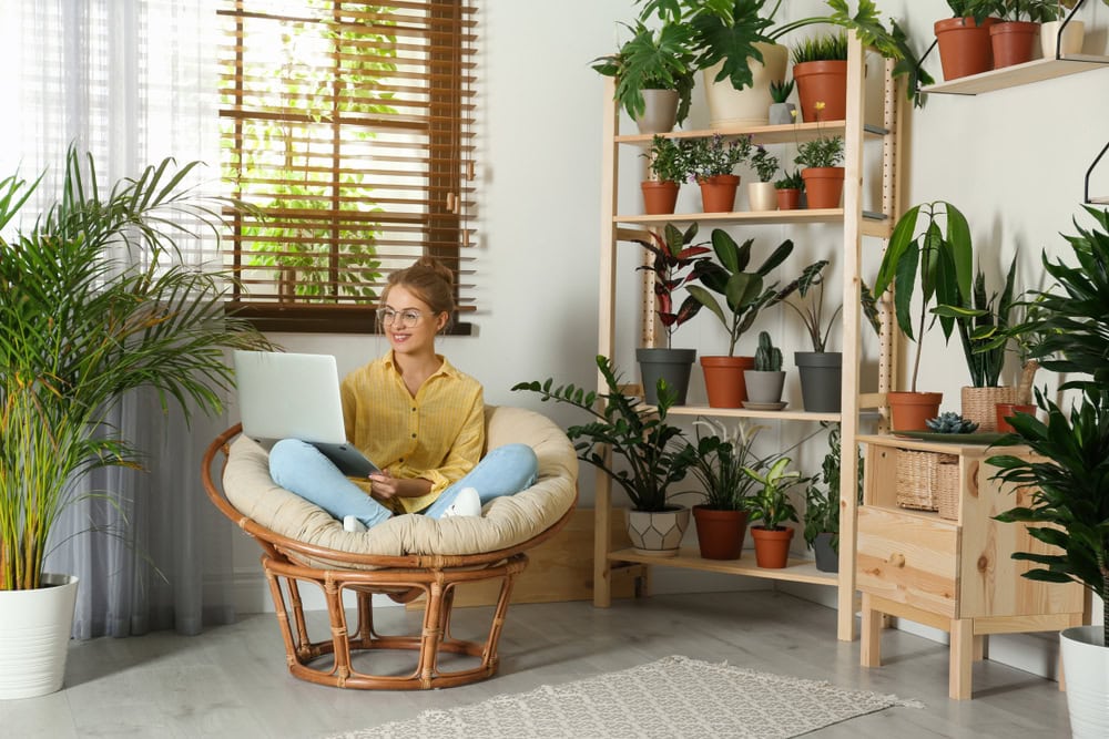 Young woman sitting in the living room filled with plants