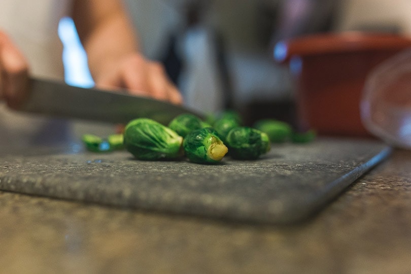 cropped person chopping brussels sprouts
