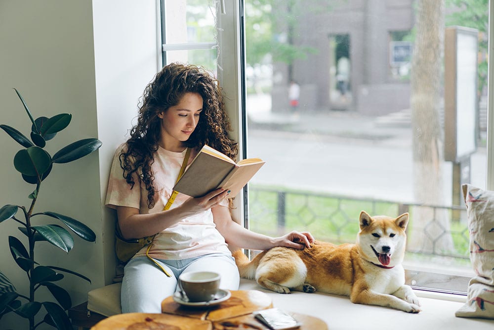 Pretty girl is reading book with shiba inu puppy