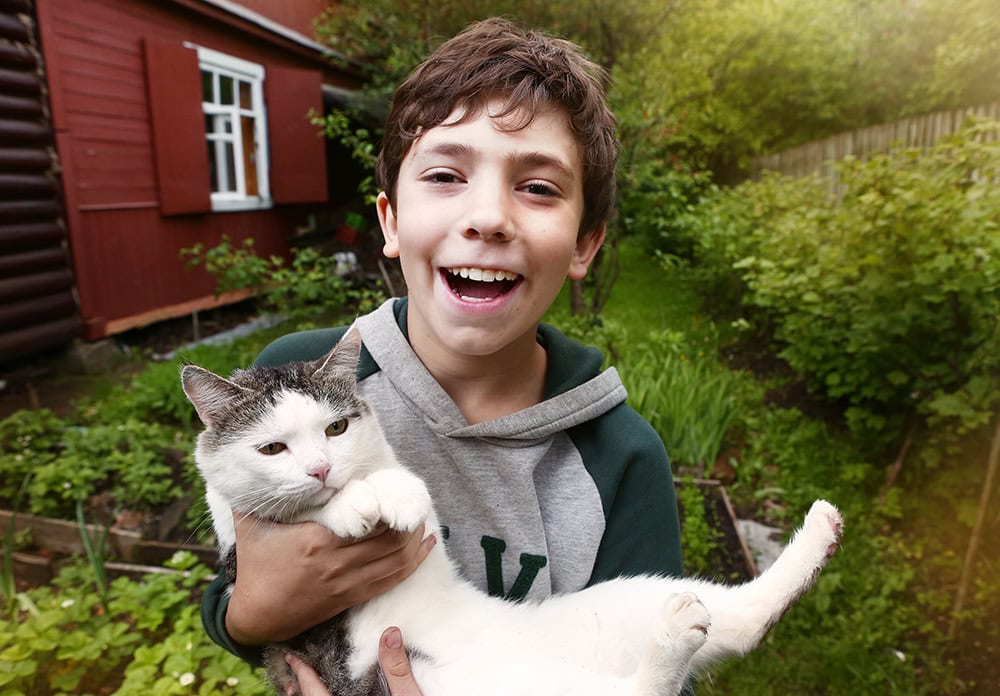 happy young boy carrying his cat
