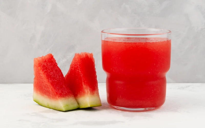 watermelon slices beside a glass of watermelon slushie