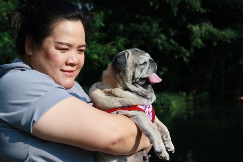 fat woman carrying pug dog
