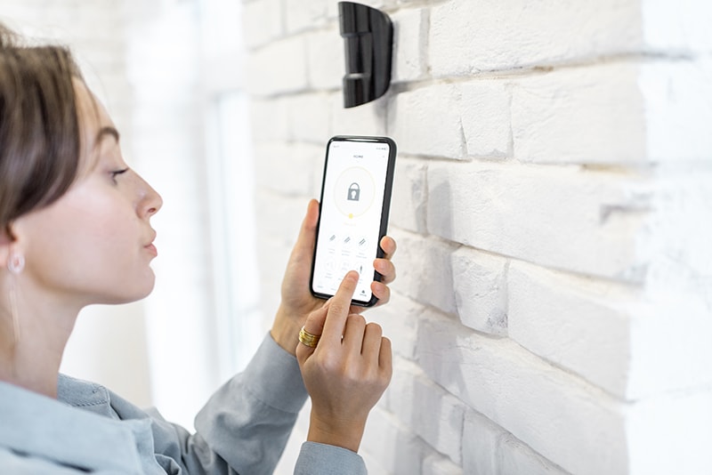 Woman controlling alarm system at home