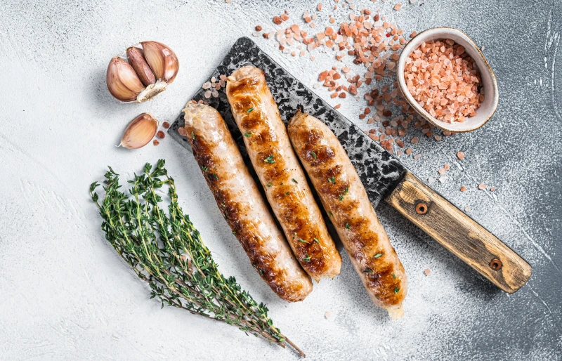 grilled bratwurst sausages on a cleaver with garlic, salt and rosemary