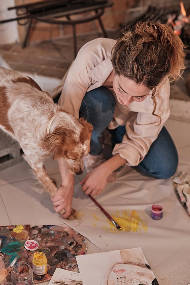 female artist and her dog making paw prints using paint