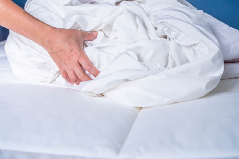 Person removing dirty linen from bed