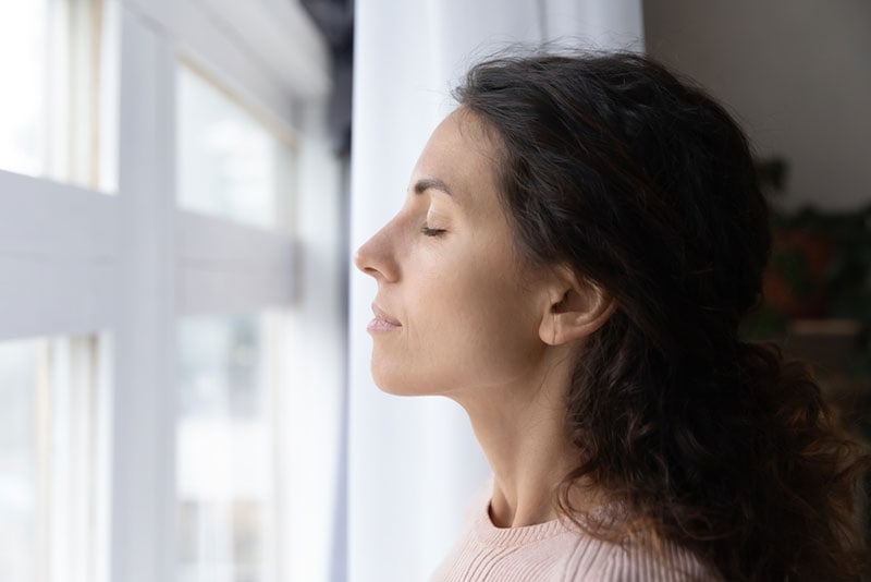 a woman breathing air with closed eyes at home