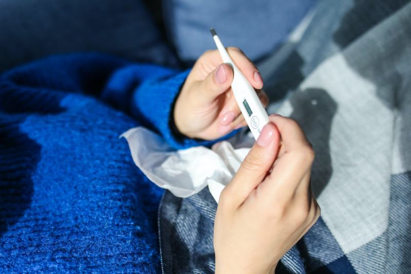 woman is sick holding a thermometer