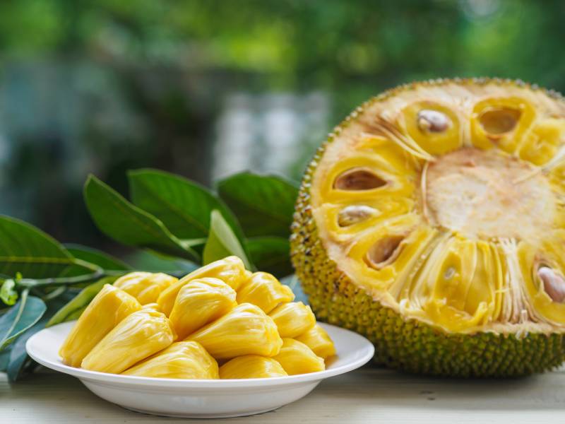 half of jack fruit and jackfruit leaf on wooden table
