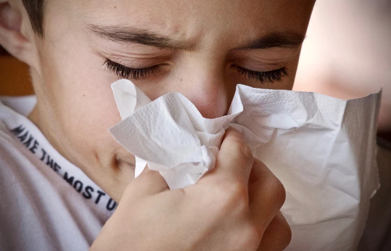 person sneezing into a tissue napkin