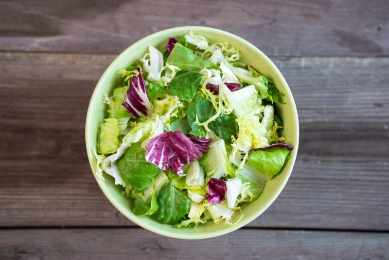 a bowl of spring salad on wooden surface