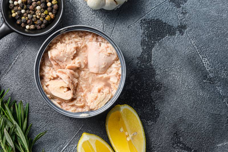 canned tuna open can with fresh herbs garlic and lemon ingredients for preservs top view