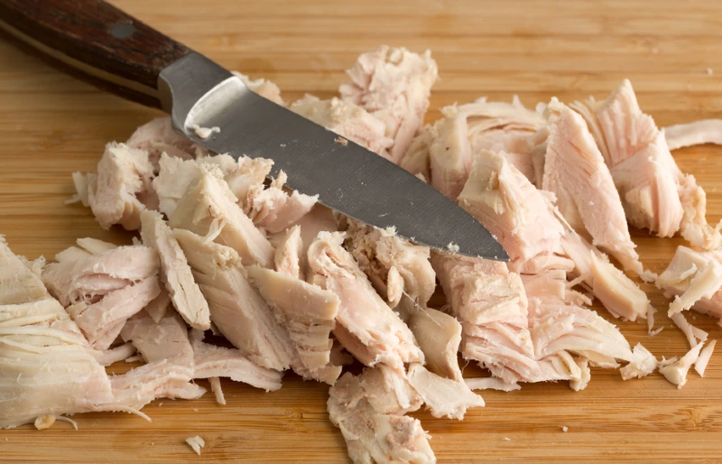chopped turkey on a wood cutting board with a knife