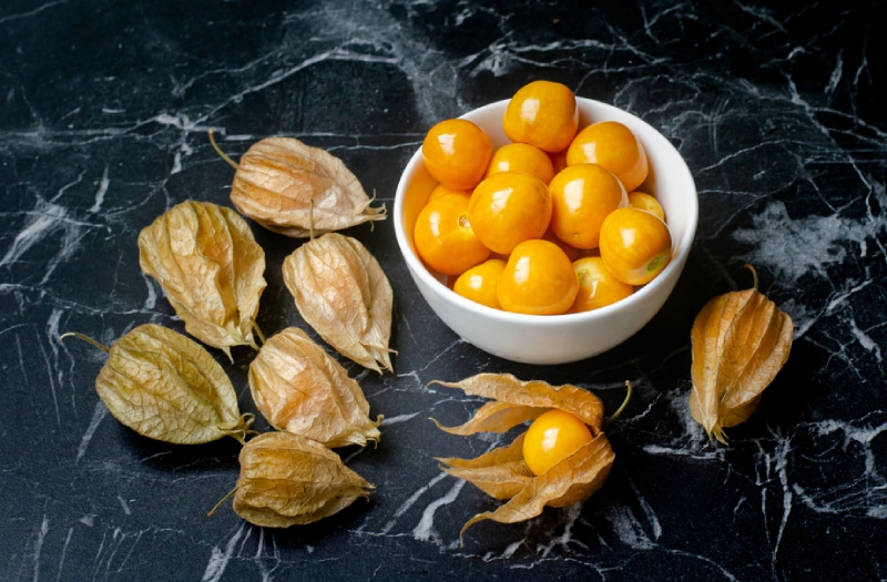 golden berries in a bowl on a black counter