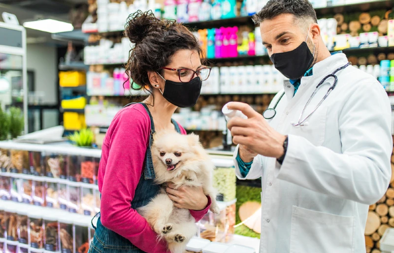woman carrying a dog consulting with veterinarian before buying medicine
