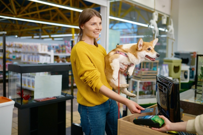 woman paying for her purchase at a pet shop with her dog