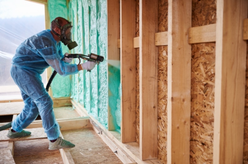 Construction guy applying spray foam on interior walls
