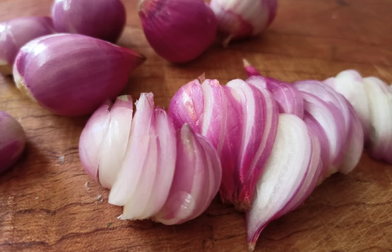 fresh sliced purple shallots on wooden chopping board