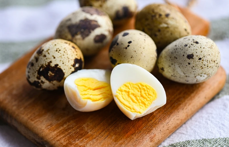 peeled and unpeeled boiled quail eggs on a wooden board