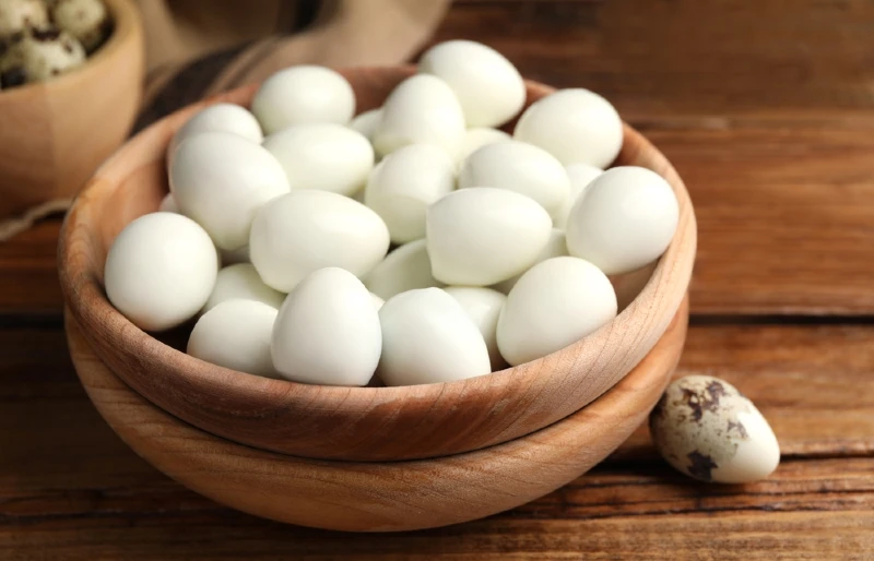 peeled boiled quail eggs in a wooden bowl