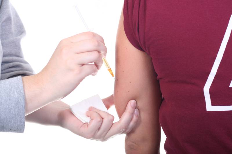 person administering an allergy shot to the woman