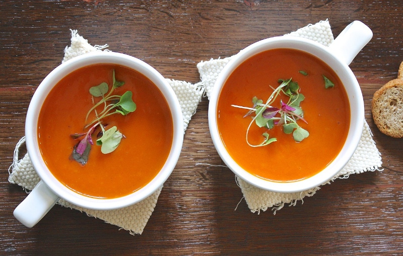 two cups of tomato soup on wooden table