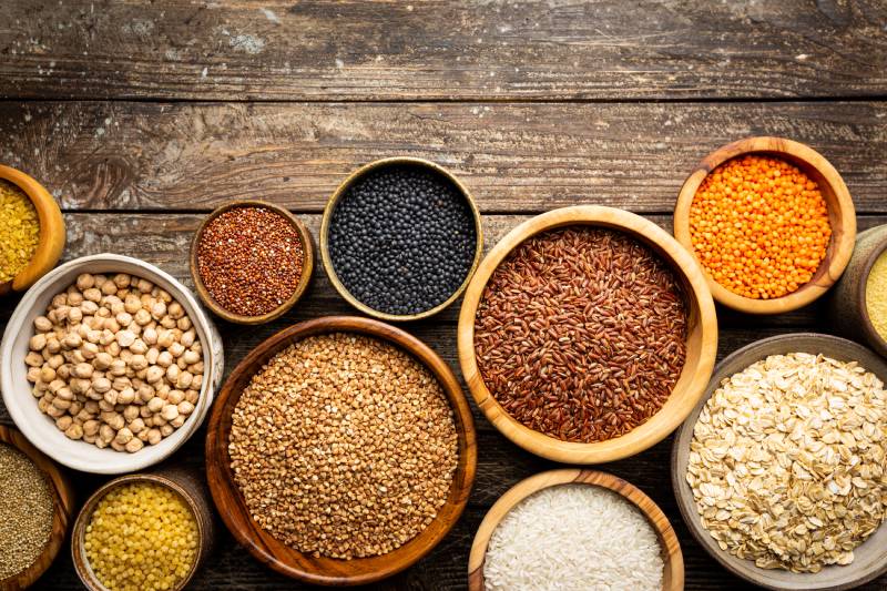 Bowls with different gluten free grains on wooden background