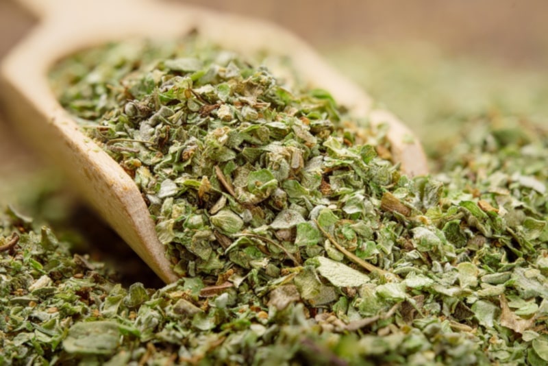 Chopped and dreid marjoram leaves in wooden scoop
