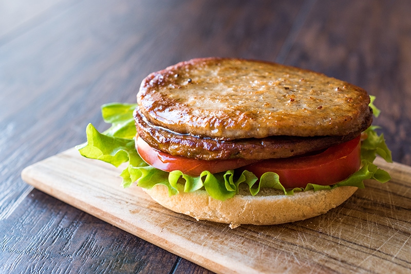 Open Double Burger with Turkey Meat, Lettuce and Tomatoes on Wooden Surface
