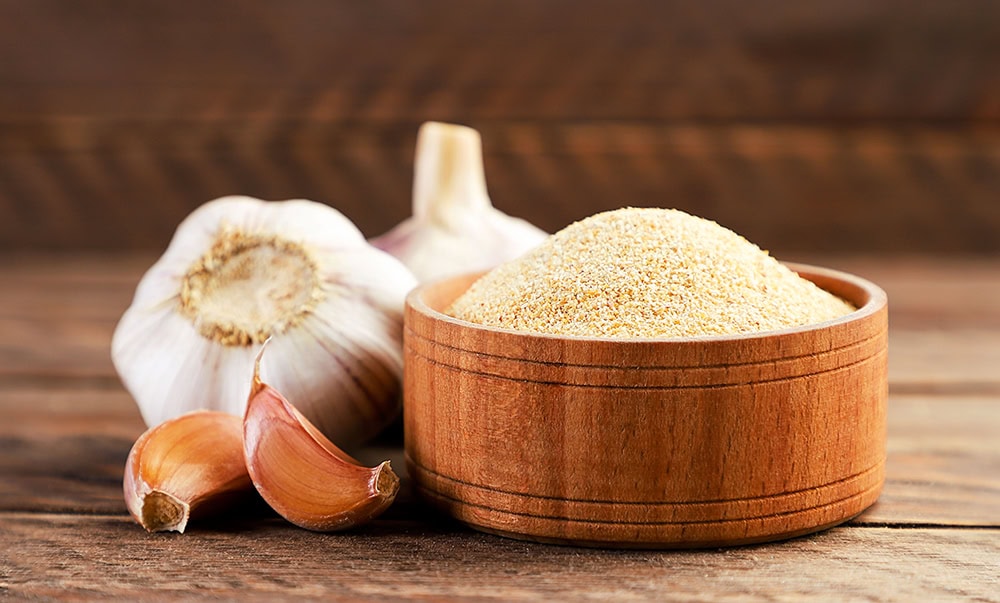 Ground garlic in wooden bowl