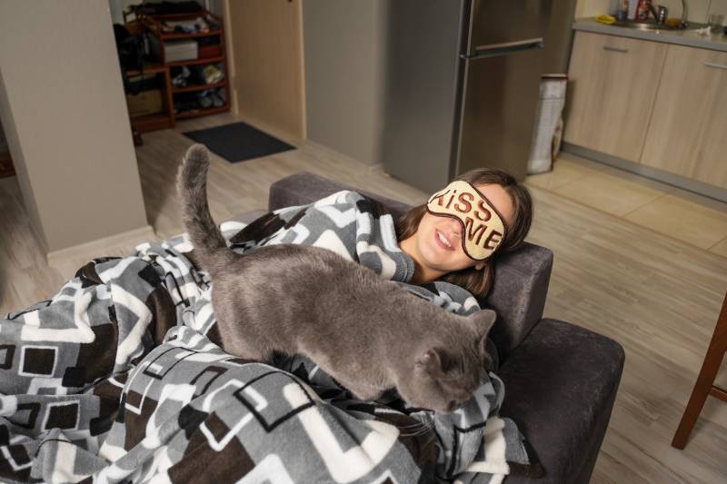woman sleeping while a cat walks