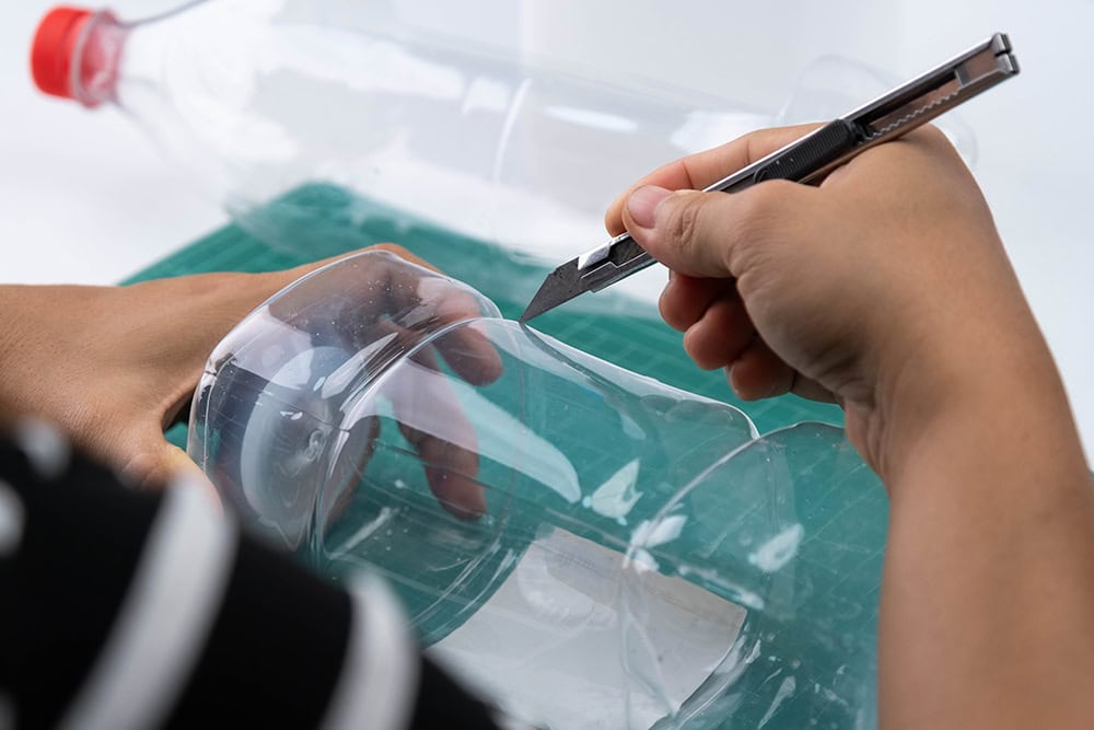 person cutting plastic bottle