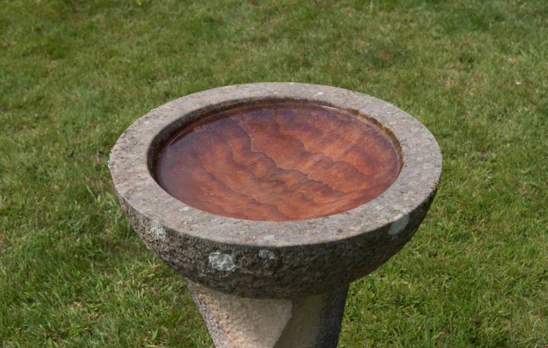 Abstract Pattern in the Bottom of a Stone Bird Bath Full of Clear Water on a Green Grass