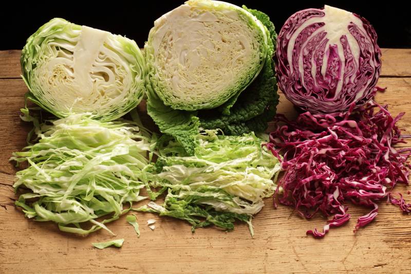Shredded red, green and Savoy cabbage, on wooden table