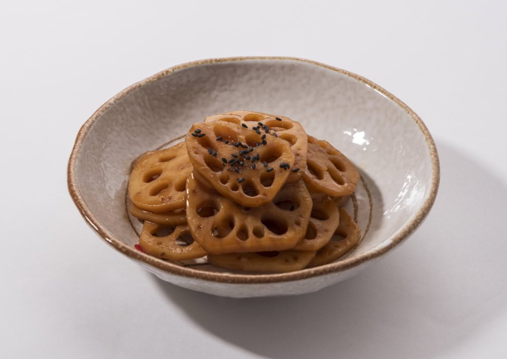 Close-up of stewed lotus roots with seasoning and black sesame seeds on dish