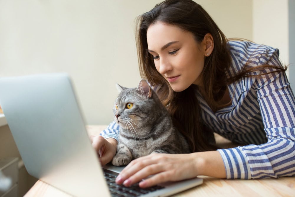 woman working on her laptop with her cat on the table